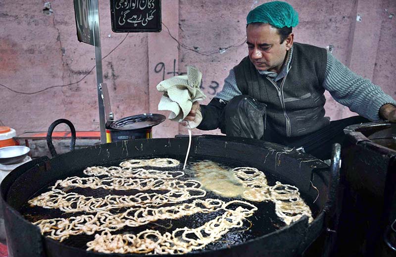 A vendor prepares sweet food item Jalebi to the customers at his roadside setup in the Provincial Capital. (APP)